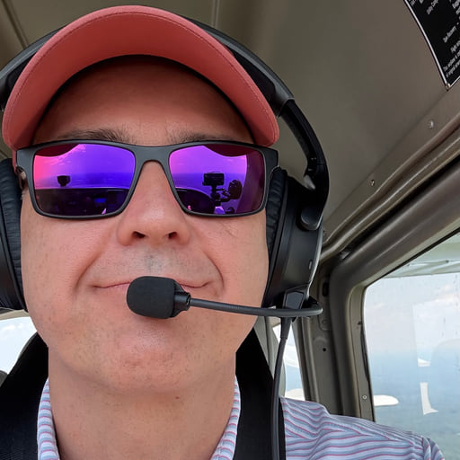 Sam LeHardy in a cockpit, wearing a headset and sunglasses